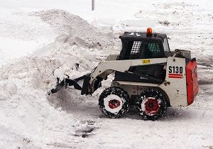 Small snowplow is cleaning the road from snowstorm.