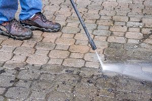 Man cleaning his patio with a pressure washer.