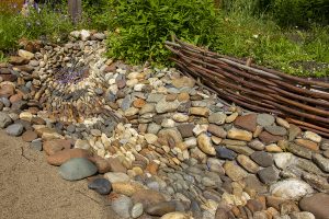 A dry stream made of large stones surrounded by a garden, exhibiting eco-friendly drainage solutions