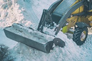 Bucket snowplow on the background of a pile of snow