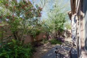 A xeriscape in a side yard making use of stones and native plants to adhere to the warm, dry climate.