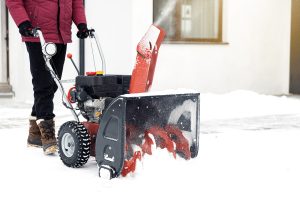 Person Snowblowing Driveway During Winter Storm
