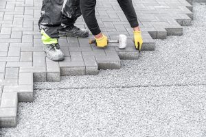 Hardscaper lays interlocking pavers in someone's driveway